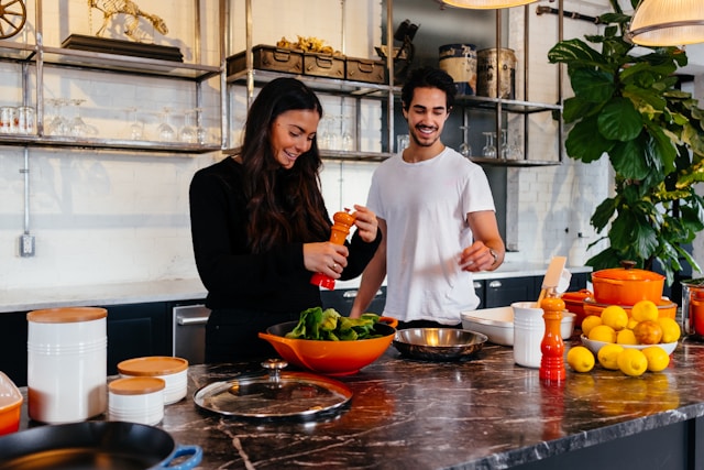 couples-cooking-together-at-home A couple smiling and laughing while preparing a meal together in a bright kitchen for a collaborative cooking date.