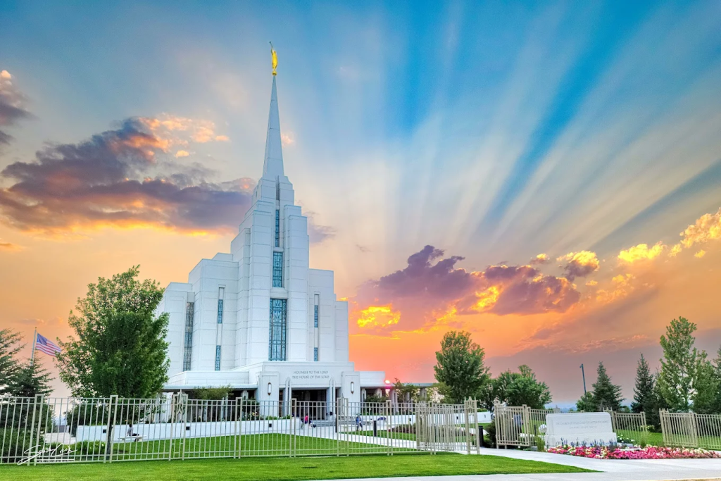 Sunset at the Rexburg Temple Gardens A wide panoramic shot of the Rexburg Idaho Temple at sunset, showing the manicured stone paths and golden light hitting the horizon.